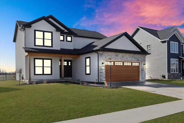 modern farmhouse featuring an attached garage, stone siding, concrete driveway, and a front yard