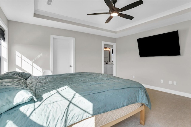 carpeted bedroom with ceiling fan, ensuite bath, a raised ceiling, and baseboards