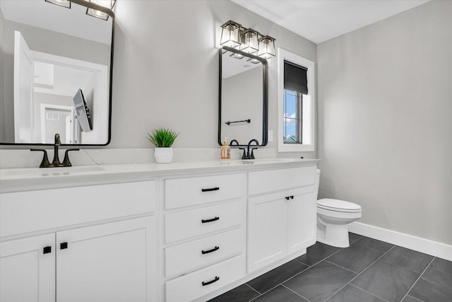 bathroom with toilet, a sink, baseboards, tile patterned floors, and double vanity