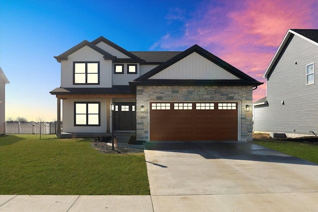 view of front of property with an attached garage, a front yard, fence, stone siding, and driveway