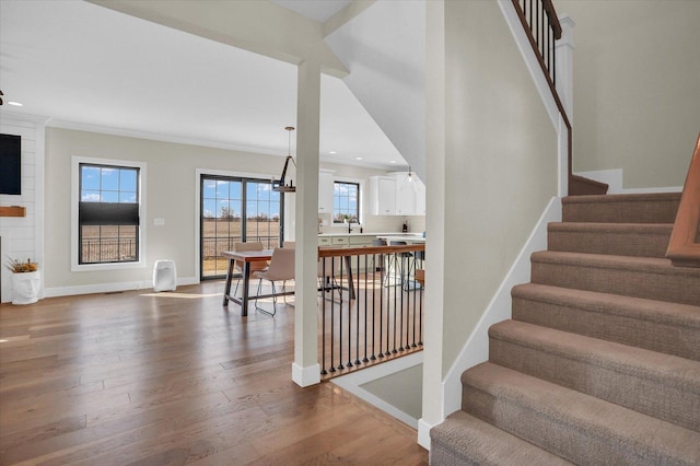 stairs with crown molding, baseboards, wood finished floors, and recessed lighting