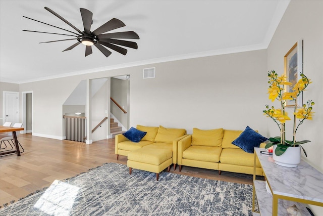 living room with ornamental molding, wood finished floors, visible vents, and baseboards