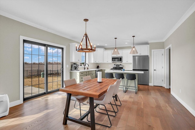 dining room with light wood-style floors, baseboards, and ornamental molding