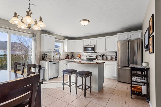 kitchen featuring light tile patterned floors, stainless steel appliances, tasteful backsplash, and white cabinets