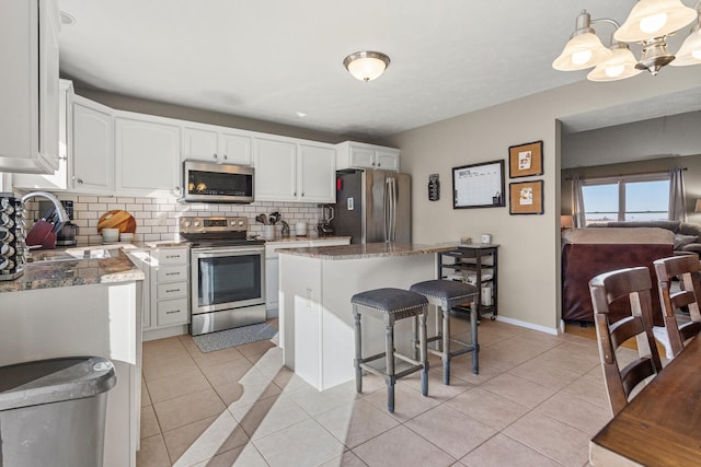 kitchen featuring tasteful backsplash, appliances with stainless steel finishes, light tile patterned flooring, a sink, and white cabinetry