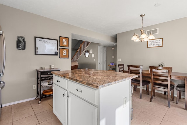 kitchen featuring light tile patterned floors, a kitchen island, visible vents, white cabinetry, and hanging light fixtures