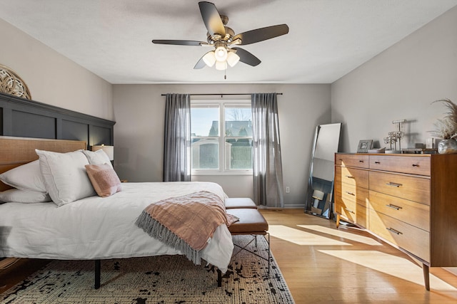 bedroom with ceiling fan, baseboards, and light wood-style floors