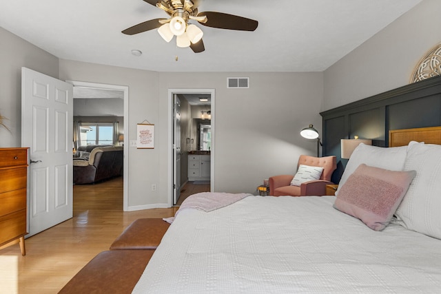 bedroom with ceiling fan, visible vents, baseboards, light wood finished floors, and ensuite bath