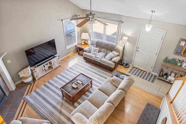 living area with a ceiling fan, tile patterned flooring, vaulted ceiling, and baseboards