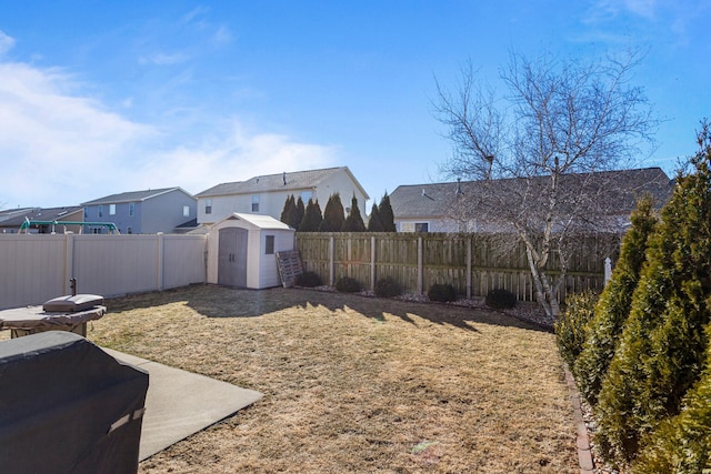 view of yard with an outbuilding, a fenced backyard, a residential view, and a storage unit