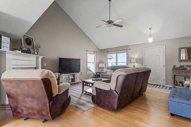 living room with high vaulted ceiling, light wood-type flooring, ceiling fan, and baseboards