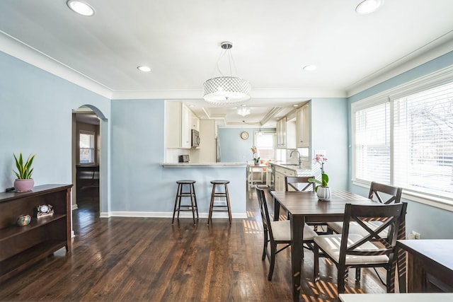 dining room featuring arched walkways, dark wood-style flooring, baseboards, and crown molding