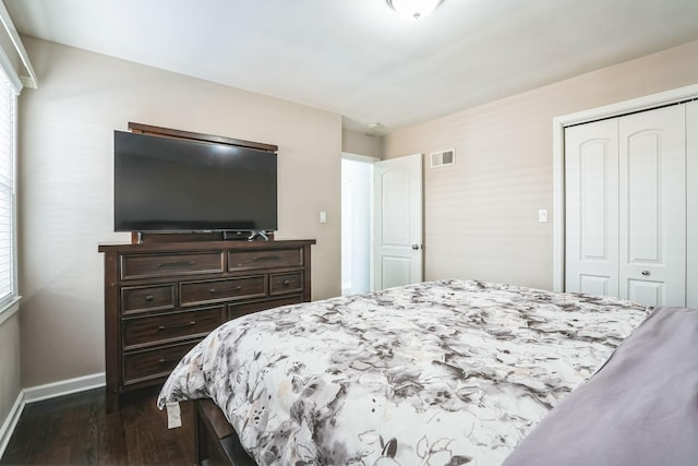 bedroom featuring dark wood-style floors, baseboards, visible vents, and a closet