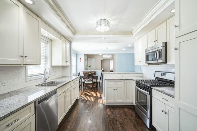 kitchen with a peninsula, a sink, white cabinetry, appliances with stainless steel finishes, and a raised ceiling