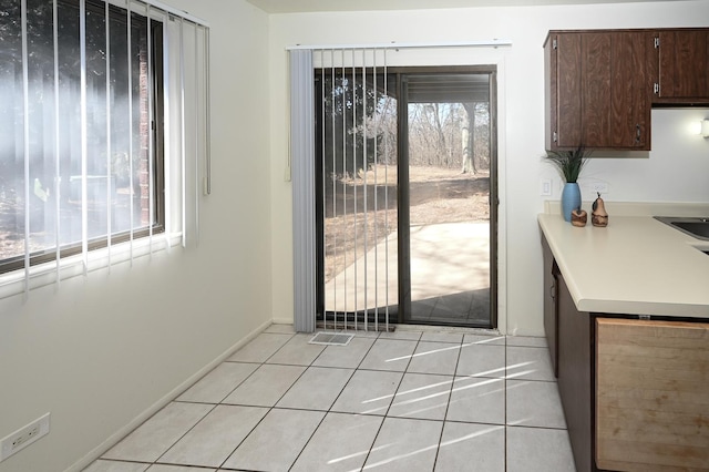 doorway to outside featuring light tile patterned floors, baseboards, and a wealth of natural light