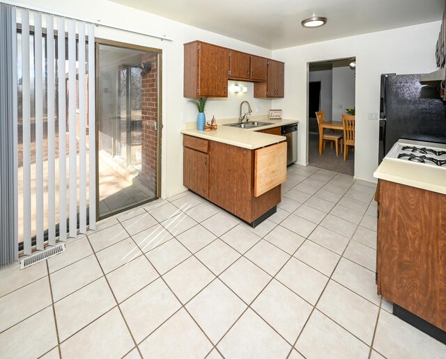 kitchen with visible vents, dishwasher, freestanding refrigerator, light countertops, and a sink