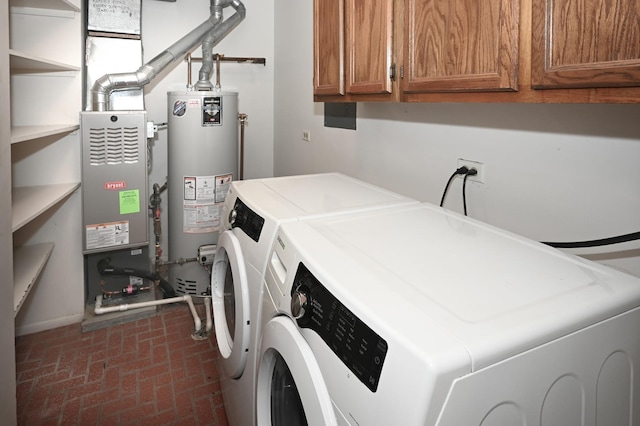 laundry room with water heater, washer and clothes dryer, brick floor, and cabinet space