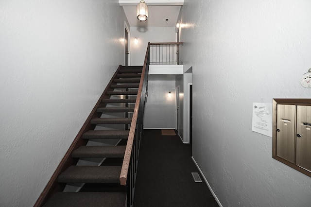 stairs with a textured wall and baseboards