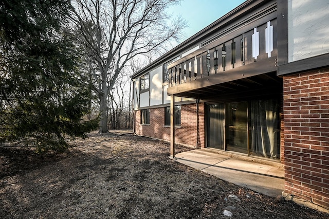 rear view of house featuring brick siding and a balcony