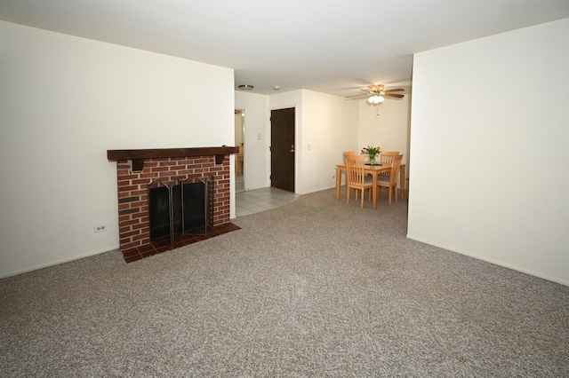 unfurnished living room with a brick fireplace, carpet flooring, and a ceiling fan