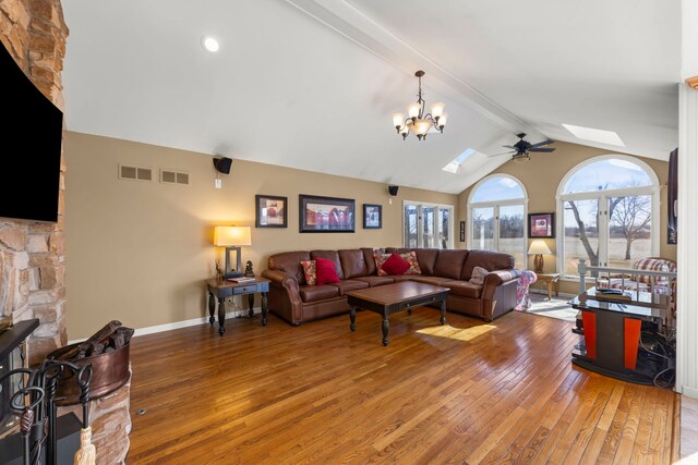 living area with lofted ceiling with skylight, visible vents, light wood-type flooring, and baseboards