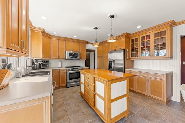 kitchen featuring a sink, wood counters, a kitchen island, stainless steel appliances, and glass insert cabinets