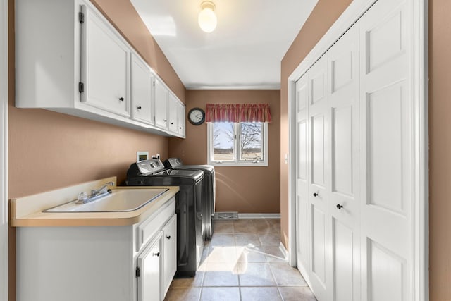 clothes washing area with light tile patterned floors, baseboards, cabinet space, a sink, and washing machine and dryer