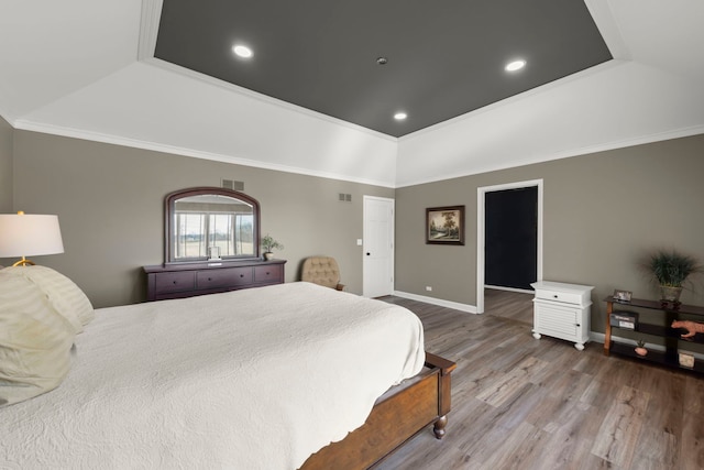 bedroom with visible vents, wood finished floors, baseboards, crown molding, and a raised ceiling