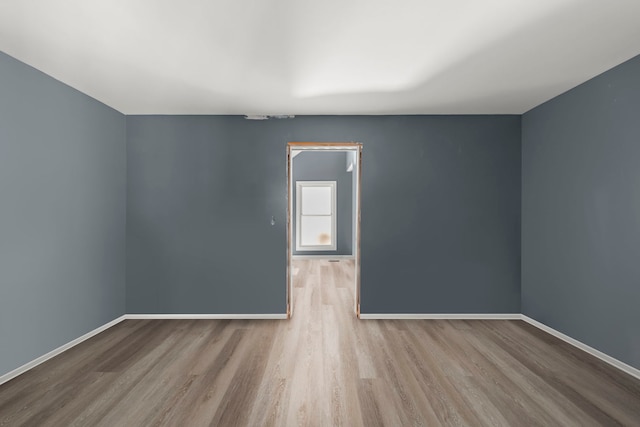 spare room featuring wood finished floors and baseboards