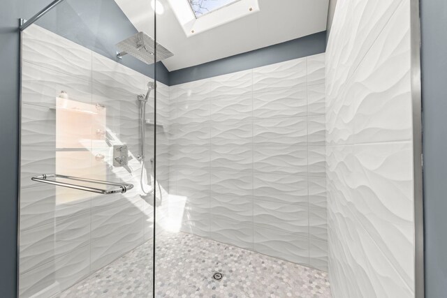 bathroom featuring a skylight, tile patterned floors, and tiled shower