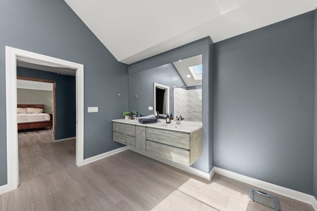 full bathroom featuring visible vents, vaulted ceiling with skylight, baseboards, and wood finished floors