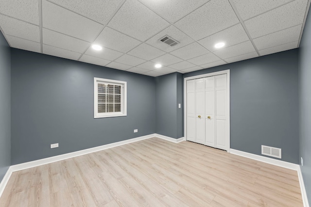 unfurnished room featuring a paneled ceiling, visible vents, baseboards, and wood finished floors