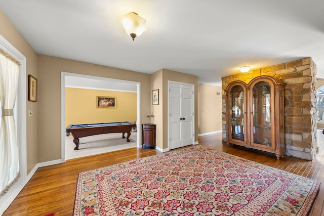 interior space with baseboards, wood finished floors, and pool table