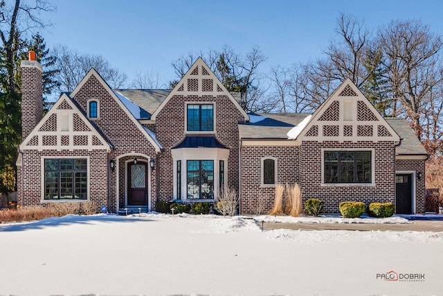 tudor home featuring brick siding and a chimney