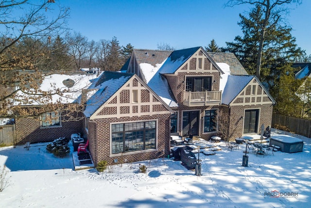 view of front of house featuring brick siding, fence, and a balcony