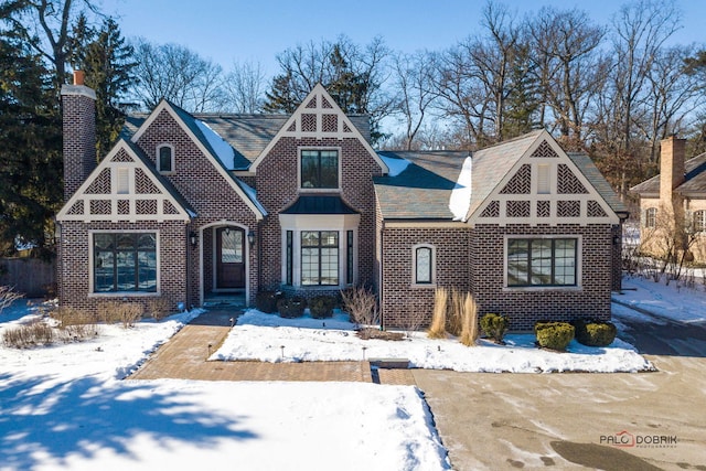 english style home featuring brick siding and a chimney