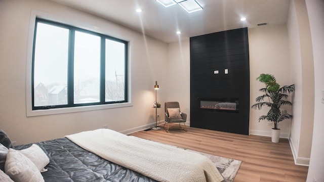 bedroom with a fireplace, baseboards, wood finished floors, and recessed lighting