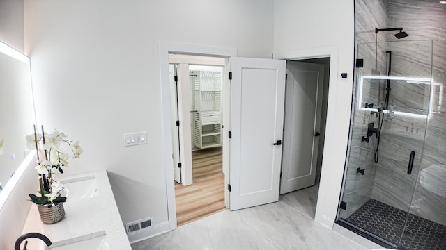 full bathroom with double vanity, a stall shower, visible vents, a spacious closet, and a sink