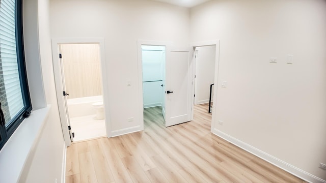 unfurnished room featuring baseboards, a high ceiling, and light wood-style floors