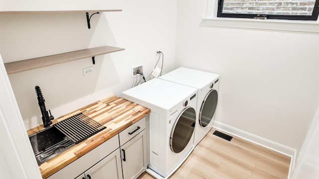 washroom with baseboards, visible vents, washer and clothes dryer, and light wood finished floors