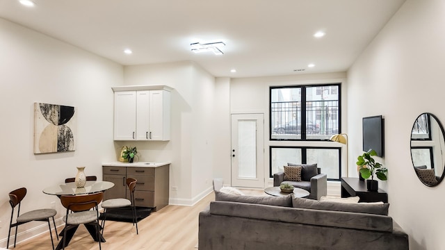 living room with arched walkways, light wood finished floors, recessed lighting, and baseboards