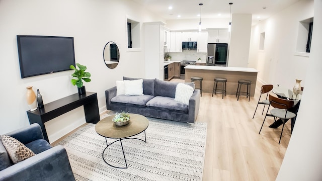 living room featuring recessed lighting, light wood-style flooring, and baseboards