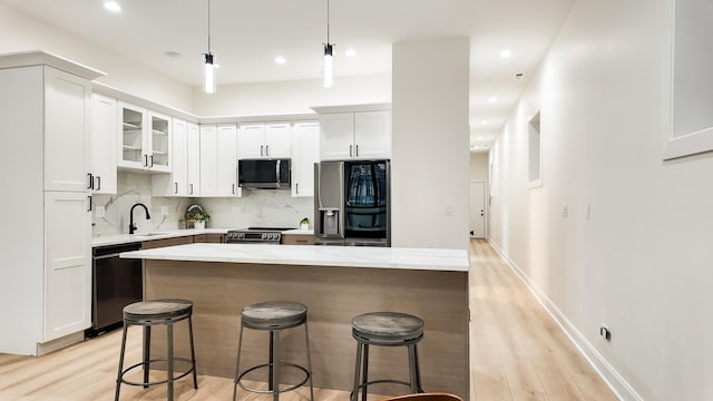 kitchen featuring stainless steel appliances, white cabinets, a center island, glass insert cabinets, and pendant lighting