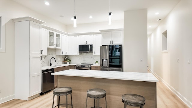 kitchen with stainless steel appliances, a center island, glass insert cabinets, and hanging light fixtures