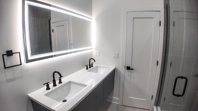 bathroom with a sink, a shower stall, and double vanity