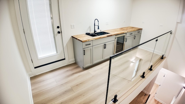 kitchen featuring butcher block counters, wine cooler, a sink, and gray cabinetry