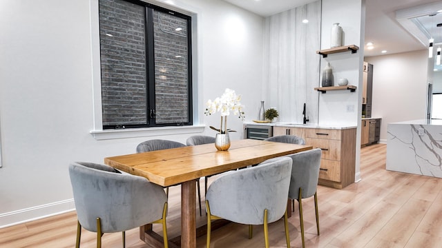 dining area with wine cooler, light wood-style flooring, and baseboards