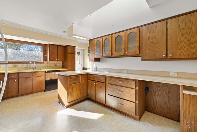 kitchen with dishwasher, glass insert cabinets, brown cabinets, light countertops, and a sink