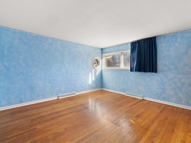 empty room featuring visible vents, baseboards, and wood finished floors