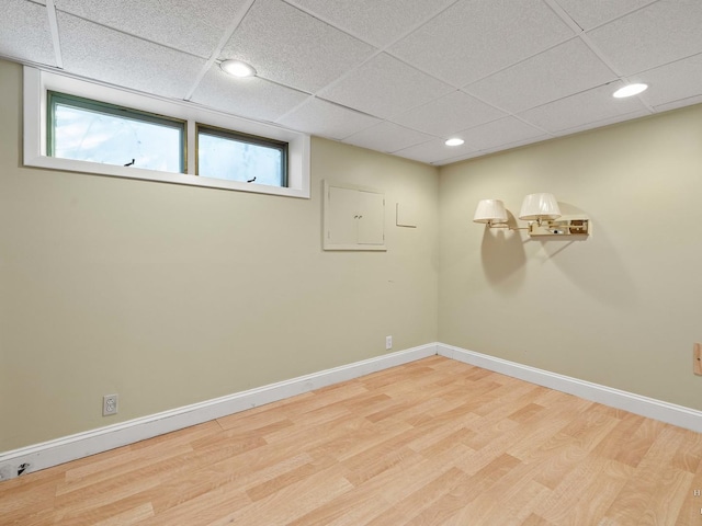 basement with a paneled ceiling, light wood-style floors, baseboards, and recessed lighting